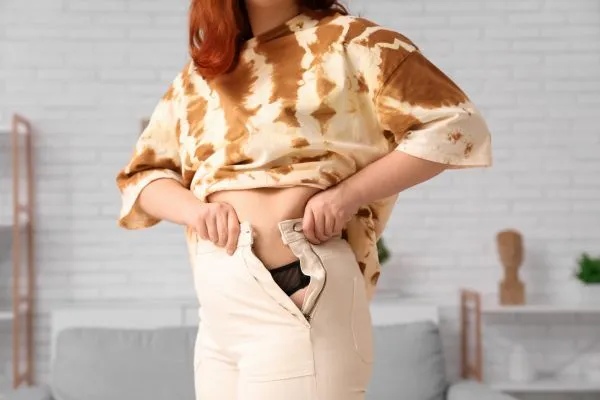 Image of woman trying to do her trousers up after pregnancy weight gain Southend