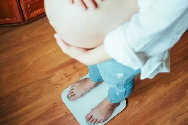 Image of woman weighing herself and experiencing weight gain through pregnancy Southend